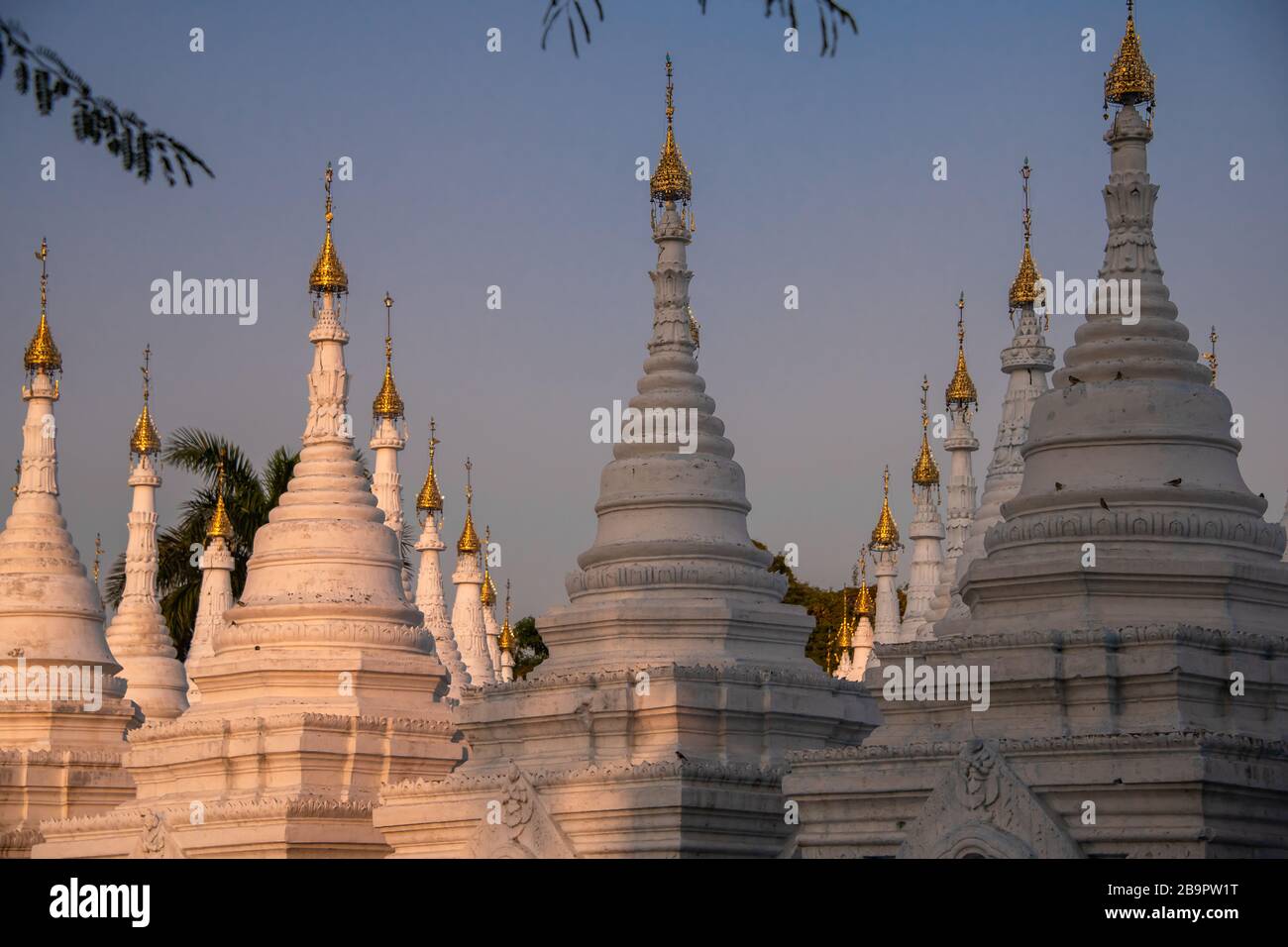 Sandamuni-Pagode, Mandalay, Myanmar. Weiße Stupas mit goldenen ornamentalen HTI-Oberteilen (schirmförmig) gegen einen Sonnenuntergang Stockfoto