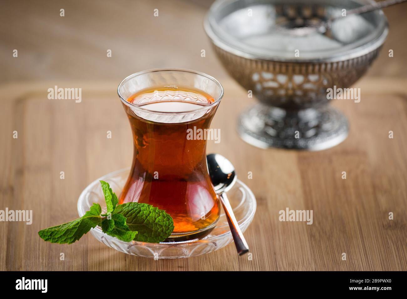 Marokkanischer Tee mit Minze und Zucker in einem Glas auf einem weißen Tisch mit einem Wasserkocher Stockfoto