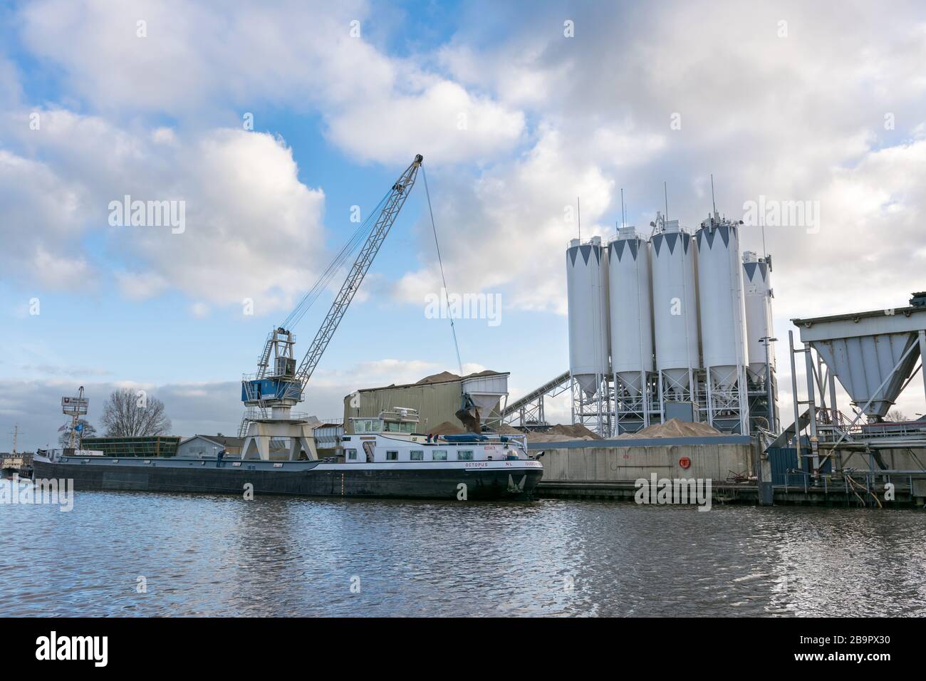 Zement- und Mörserindustrie mit großem Kran entlang des Flusses Gouwe in Gouda, Holland. Stockfoto