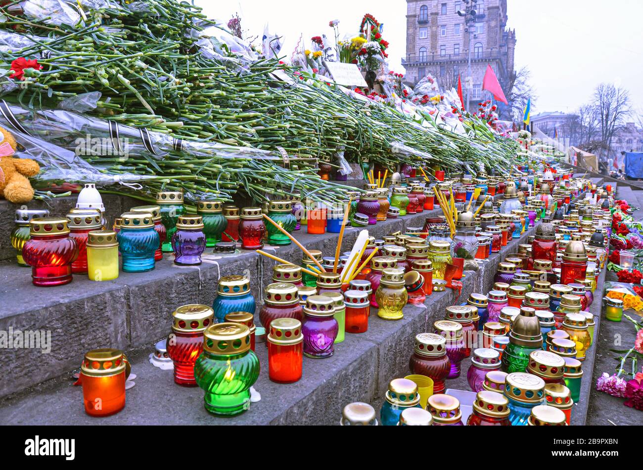 Kirchenlaternen und Kerzen in Erinnerung an Verstorbene. Verschiedene Farben Kerzen auf Stufen. Glaslaternen. Stockfoto
