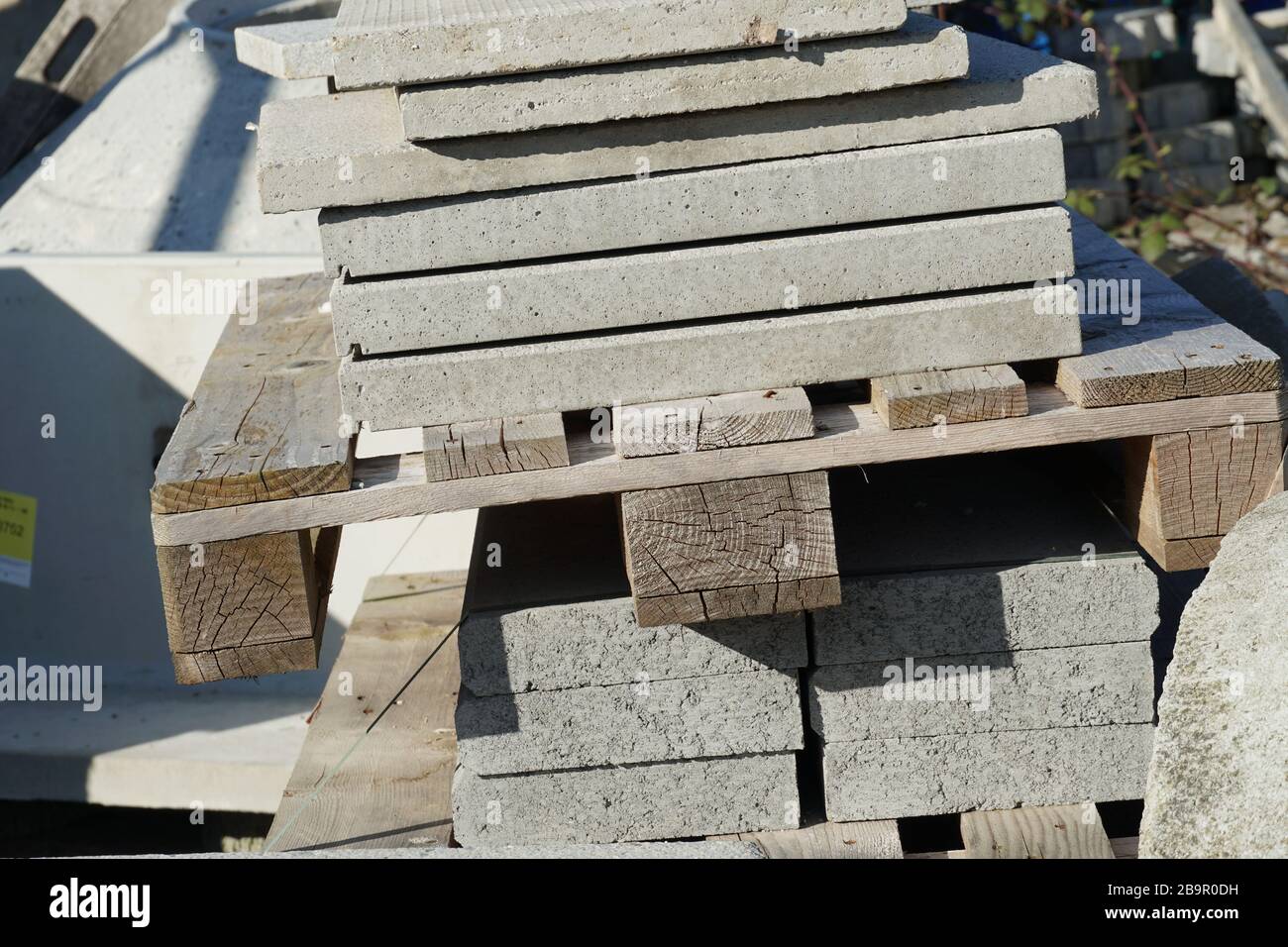 Betonplatten oder Kopfsteinpflaster großer Dimension, die auf Holzpaletten in der Lagerung von Gebäude oder Baumaterial gehockt sind, Nahansicht Stockfoto