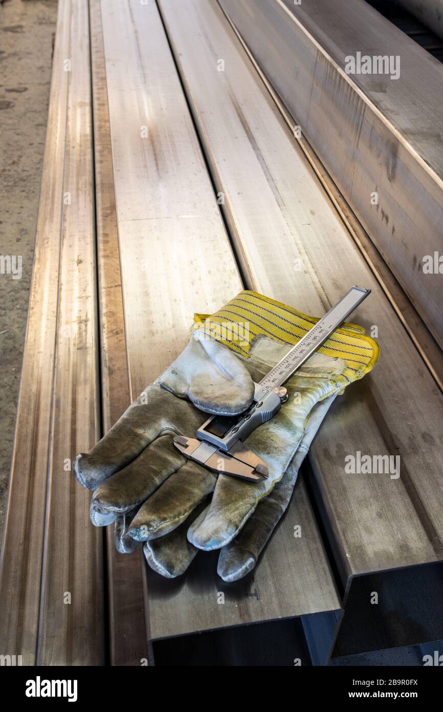 Sehr alte Arbeitshandschuhe an Edelstahlrohren mit Bremssattellehre Stockfoto Sehr alte Arbeitshandschuhe an Edelstahlrohren mit Bremssattellehre Stockfoto