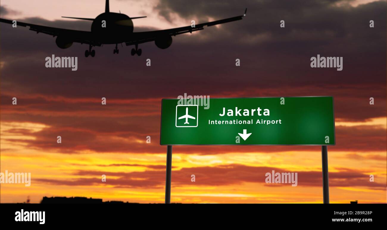 Flugzeug Silhouette Landung in Jakarta, Indonesien. Ankunft in der Stadt mit Hinweisschild zum Flughafen und Sonnenuntergang im Hintergrund. Reise- und Transportkosten Stockfoto