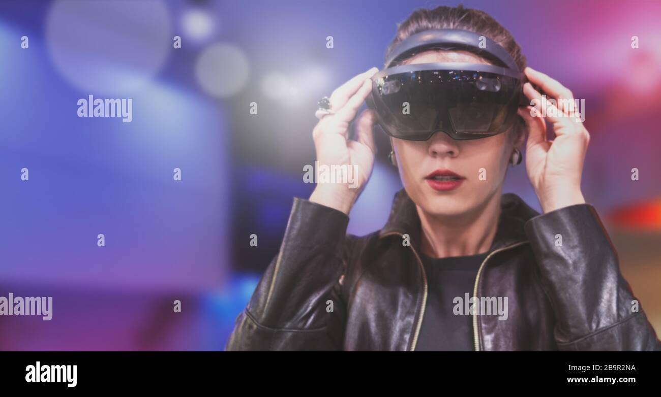 Portrait der jungen kaukasischen Frau unter Verwendung der erweiterten und virtuellen Realität mit holografischen Hololen-Brillen. Rosa, Magenta und blauer Hintergrund. Future tec Stockfoto