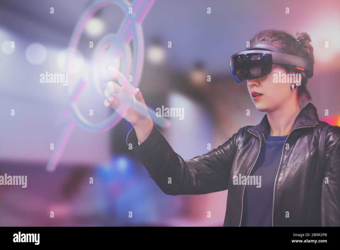 Portrait der jungen kaukasischen Frau unter Verwendung der erweiterten und virtuellen Realität mit holografischen Hololen-Brillen. Unscharfer Hintergrund in Pink, Magenta und Blau. Fu Stockfoto