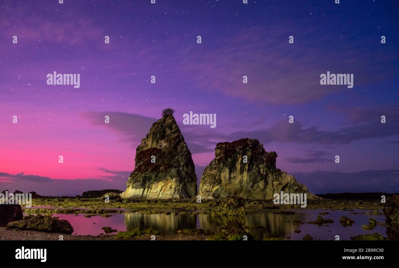 Karang Layar einzigartige Felsformationen am frühen Morgen lebhafter violetter Sonnenaufgang. Wunderschönes Spiegelbild in Niedrigwasser in der Nähe des Indischen Ozeans, Sawarna, Banten, Stockfoto