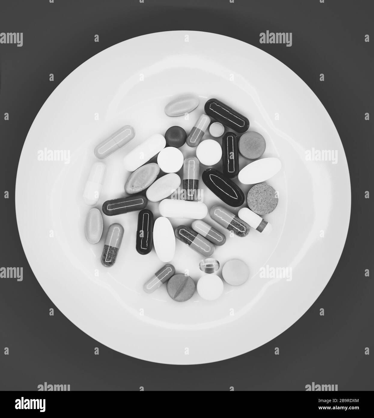 Weiße Platte mit pharmazeutischen Pillen auf rotem Hintergrund Stockfoto