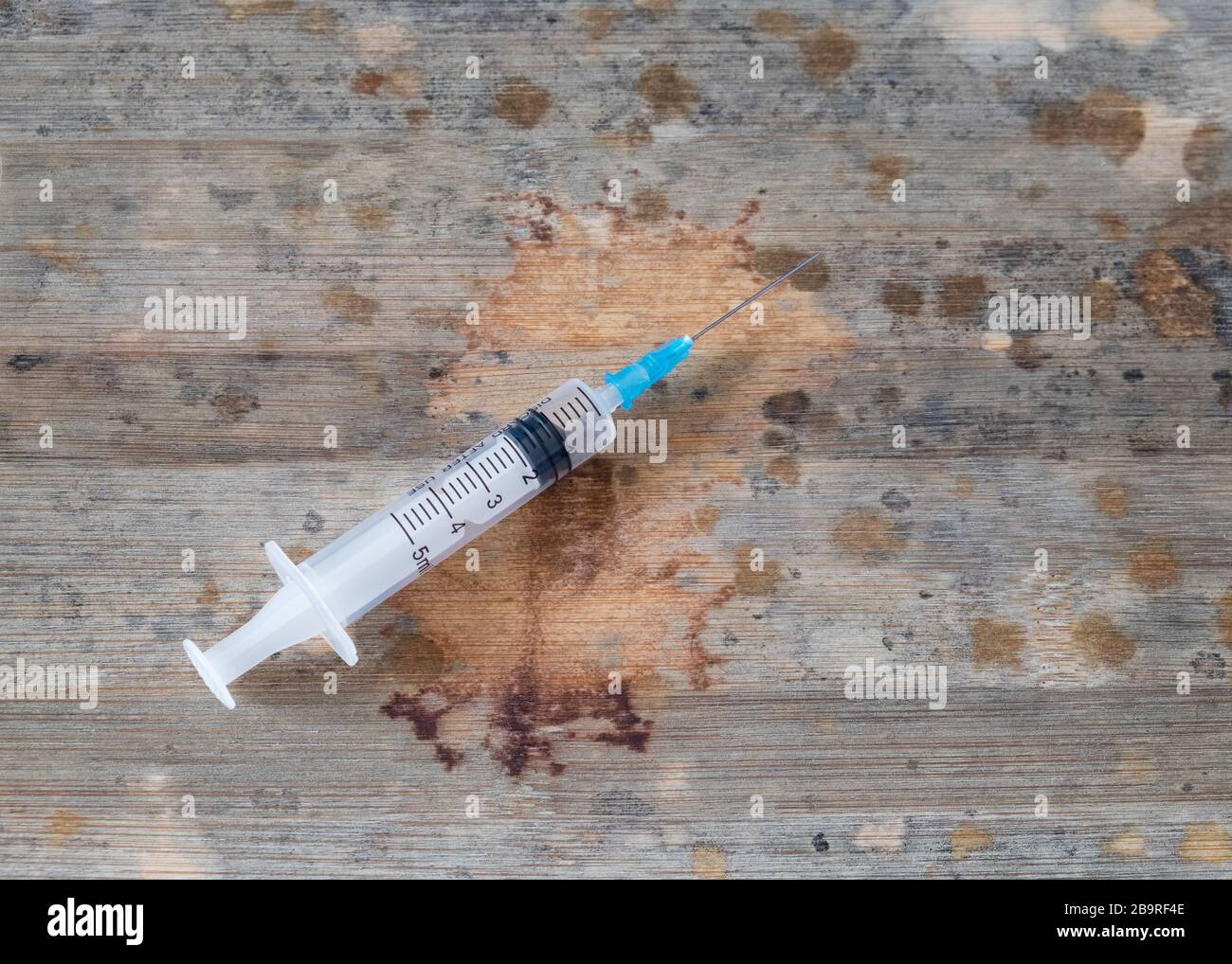Impfkonzept, Spritze auf Holzbrett mit vielen Stellen, die an die Entwicklung des Virus erinnern. Stockfoto