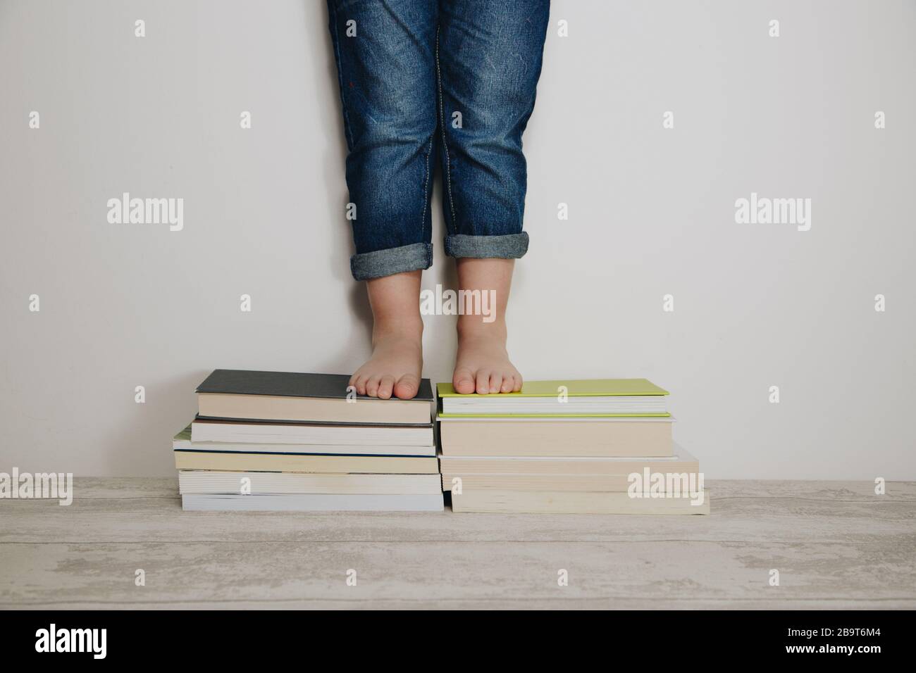 Kind steht auf Stapel von Büchern. Weltbuch-Tageskonzept Stockfoto