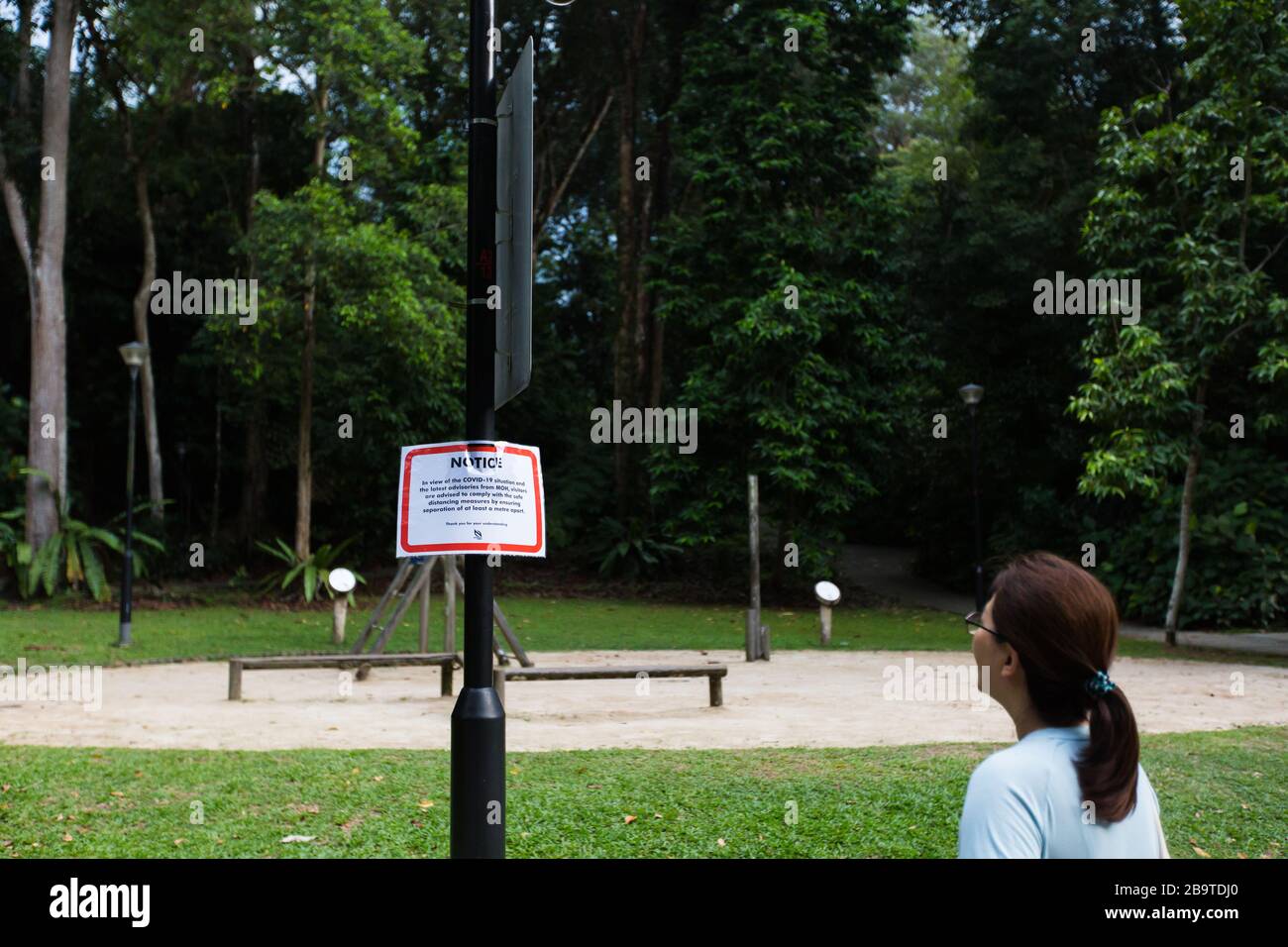 Eine Dame, die die Mitteilung im Hinblick auf die COVID-10-Situation des Gesundheitsministeriums im öffentlichen Raum, Singapur, Südost-Asien, gelesen hat Stockfoto