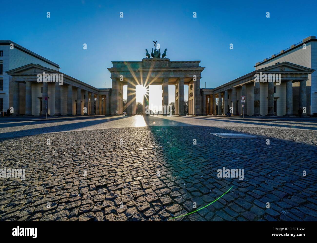 23.03.2020, das Brandenburger Ziel in Berlin an einem späten Frühlingssaftstag in der tiefen Sonne. Die Sonne scheint durch die Prophylaxe und erzeugt eine besondere Licht- und Schattenstimmung. Wegen der Koronakrise sind in Berlin nur wenige Menschen auf den Straßen und Plätzen. Weltweite Verwendung Stockfoto