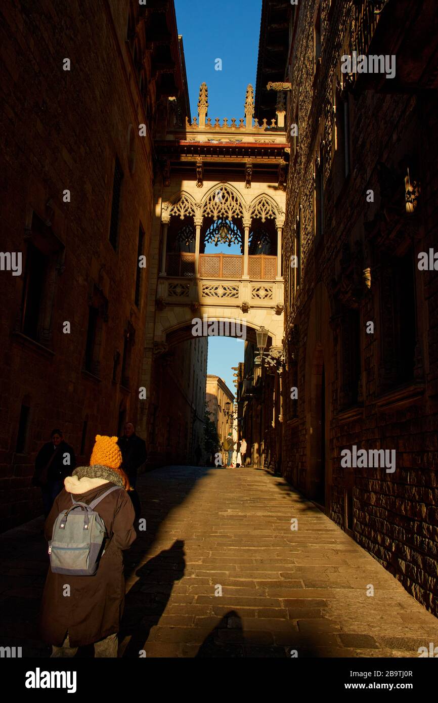 Menschen, die bei Sonnenaufgang auf der Bari Gotic in Barcelona, Spanien, unter der Pont del Bisbe spazieren Stockfoto