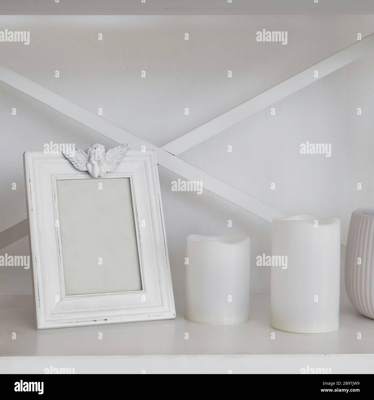 Leerer weißer Holzrahmen und weiße Kerzen auf Holzregal mit Kopierraum Stockfoto