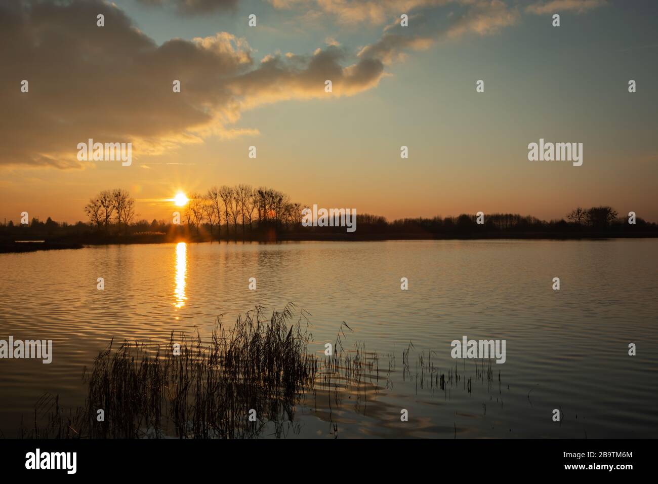 Sonne untergehen und sich über einen ruhigen See mit Blick auf den Abend wolken Stockfoto
