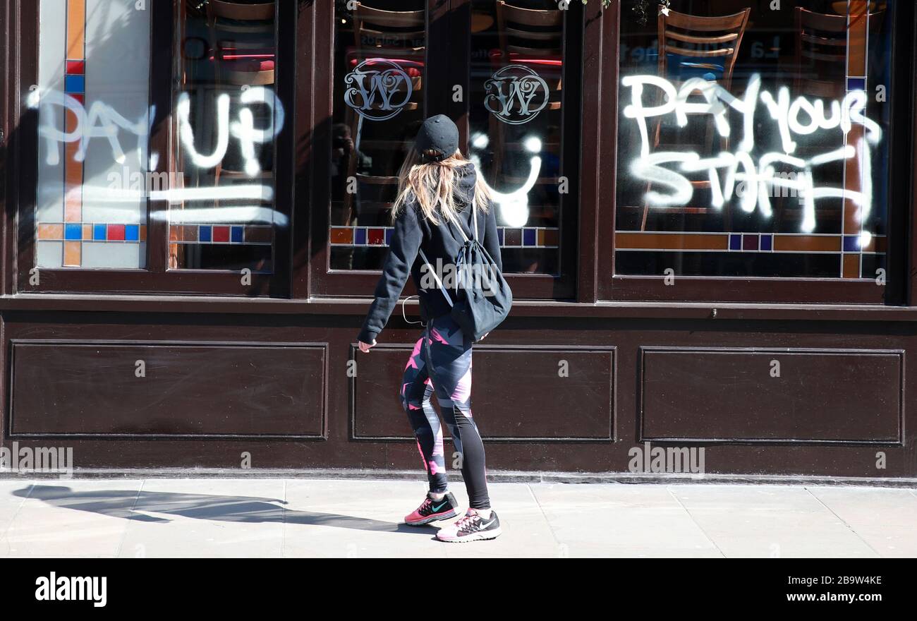 Eine Person betrachtet Graffiti auf einem JD Wetherspoon Pub in Crystal Palace, South London. Die Mitarbeiter von Wetherspoons haben Gründer Tim Martins fehlende Unterstützung für die 40.000 Mitarbeiter seiner Kette als "absolut ungeheuerlich" bezeichnet. Stockfoto