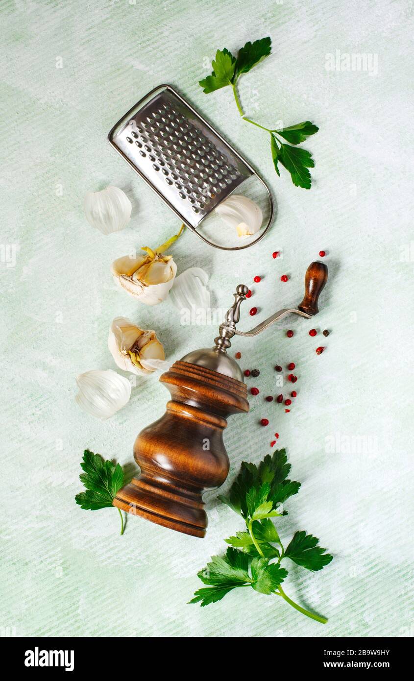 Pfeffermühle, Grat, Knoblauch und Petersilie auf hellem Hintergrund. Stockfoto