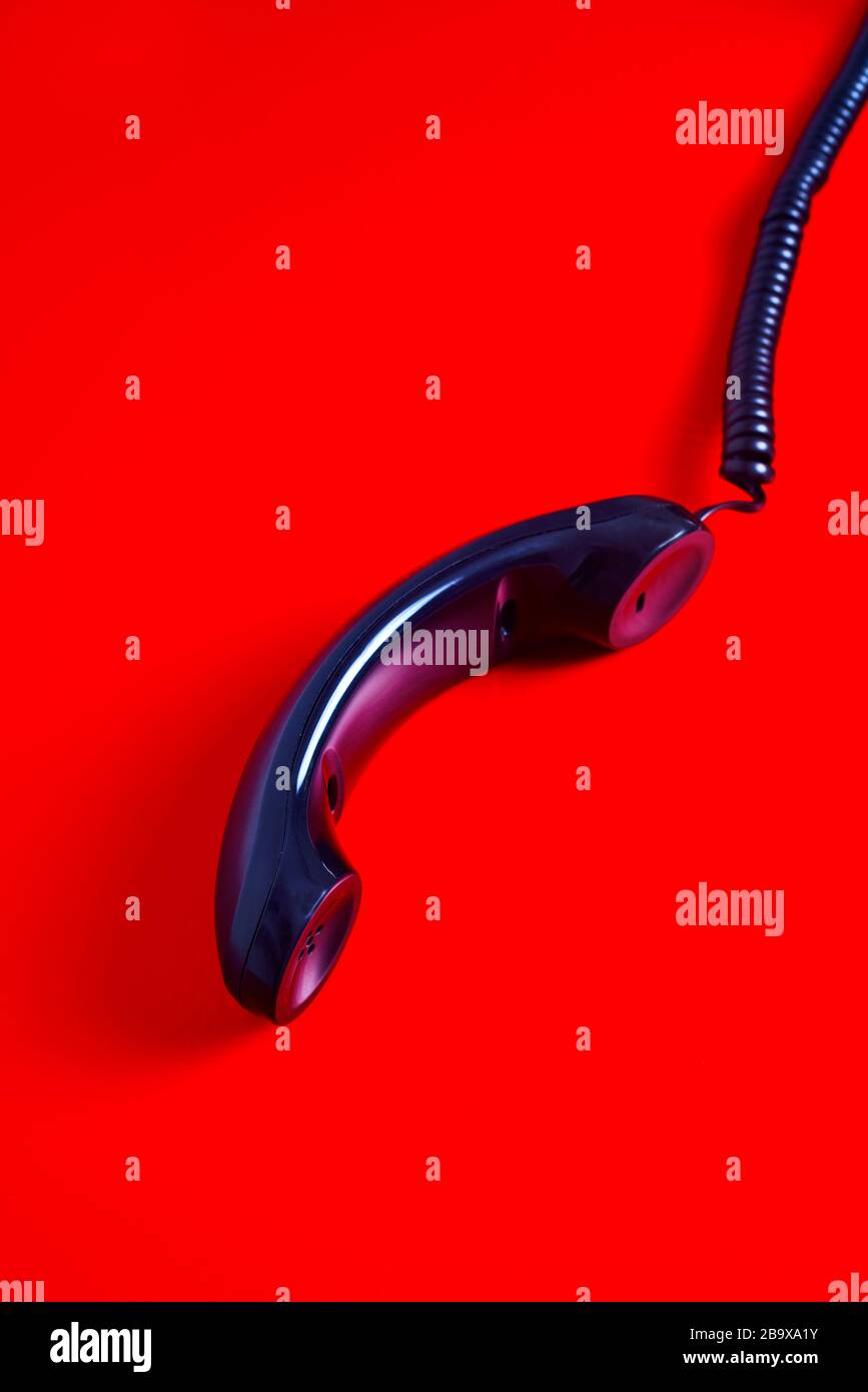 Nahaufnahme des Mobilteils eines schwarzen Telefons im roten Hintergrund Stockfoto