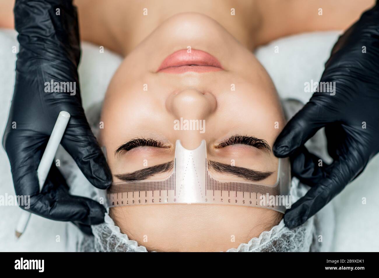Markup mit Lineal an den Augenbrauen während des permanenten Make-up. Stockfoto
