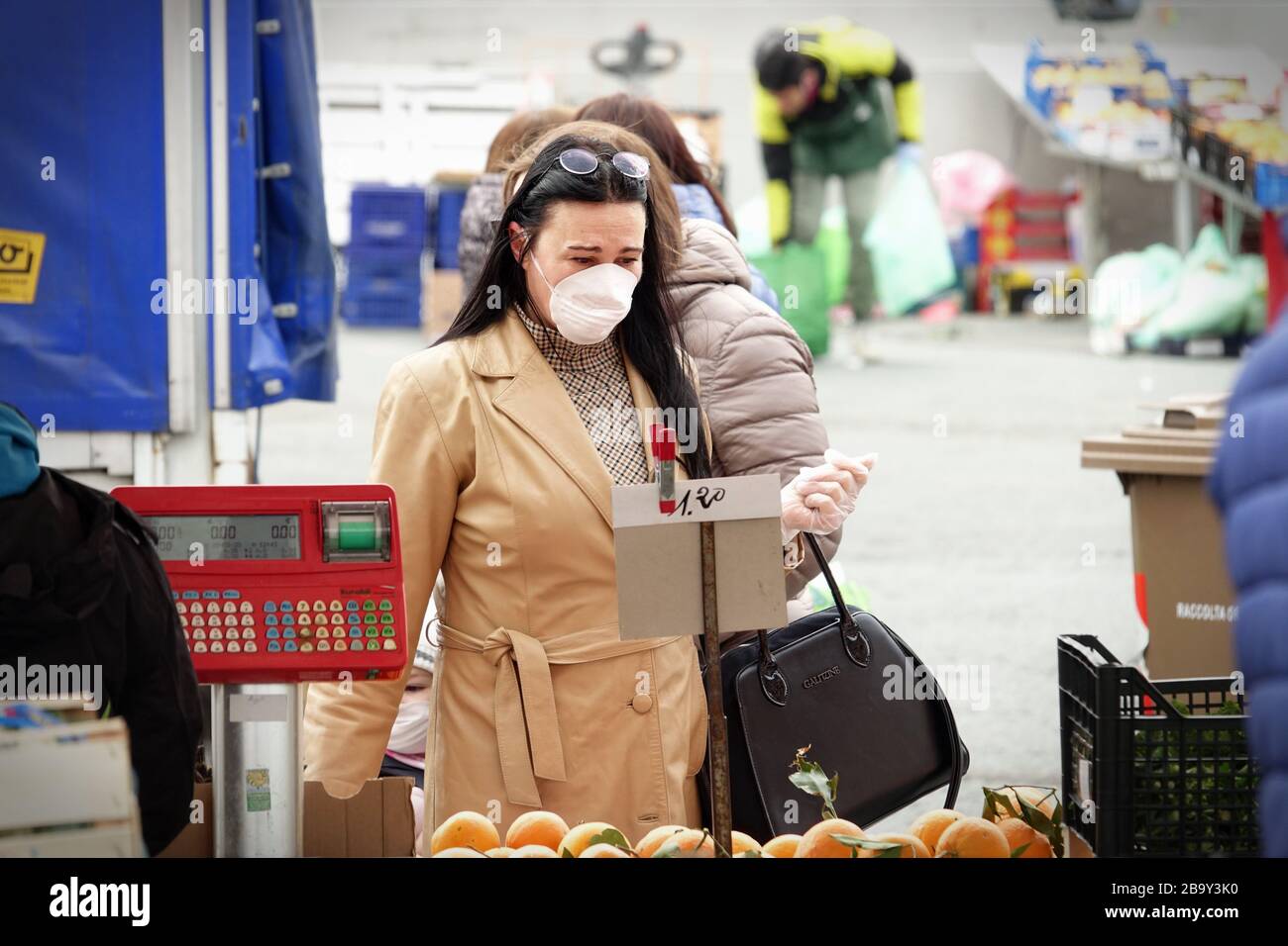Menschen mit Gesichtsmasken zum Schutz vor COVID-19 kaufen auf dem Markt Gemüse und Obst ein. Turin, Italien - März 2020 Stockfoto
