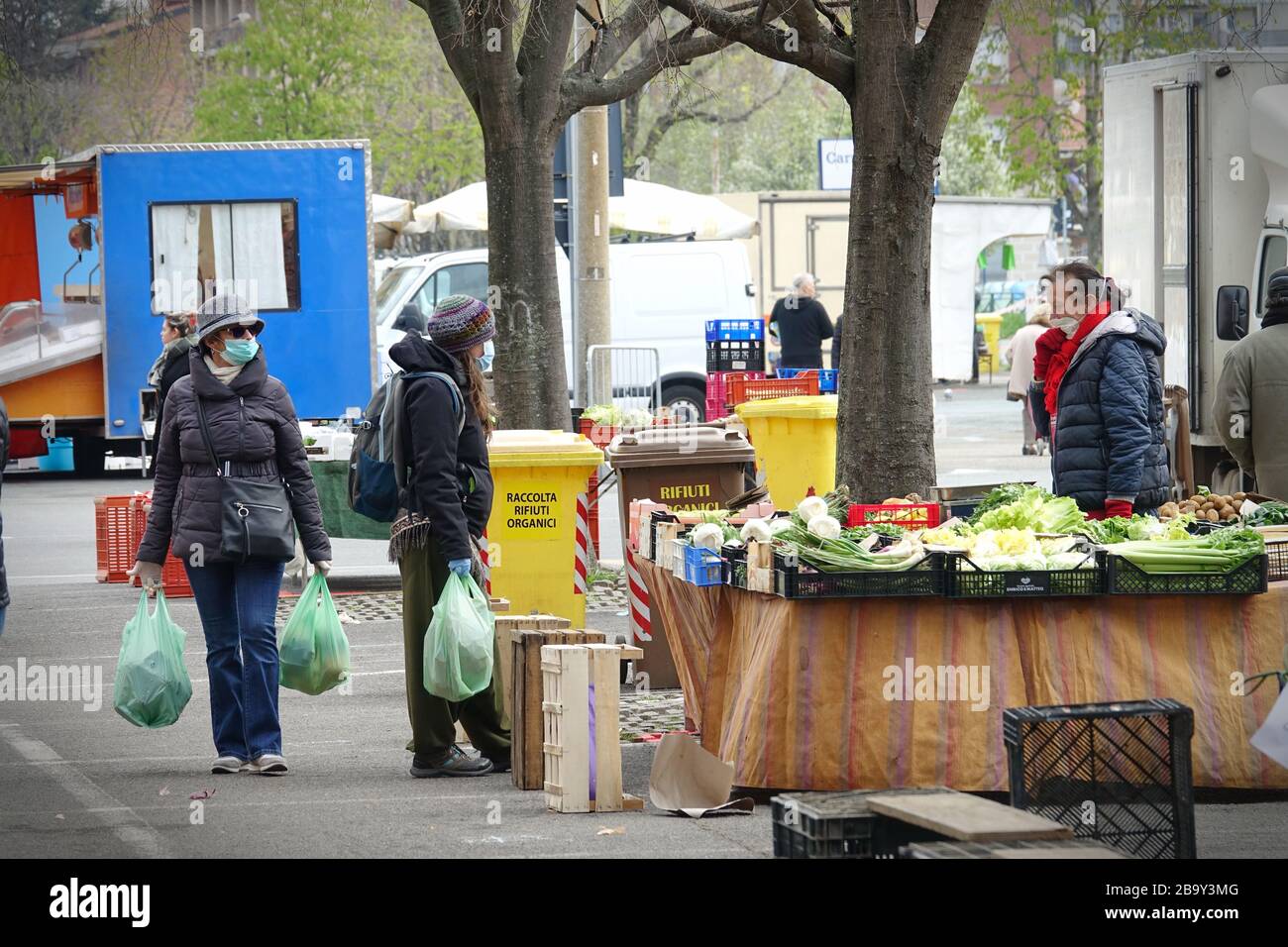 Menschen mit Gesichtsmasken zum Schutz vor COVID-19 kaufen auf dem Markt Gemüse und Obst ein. Turin, Italien - März 2020 Stockfoto