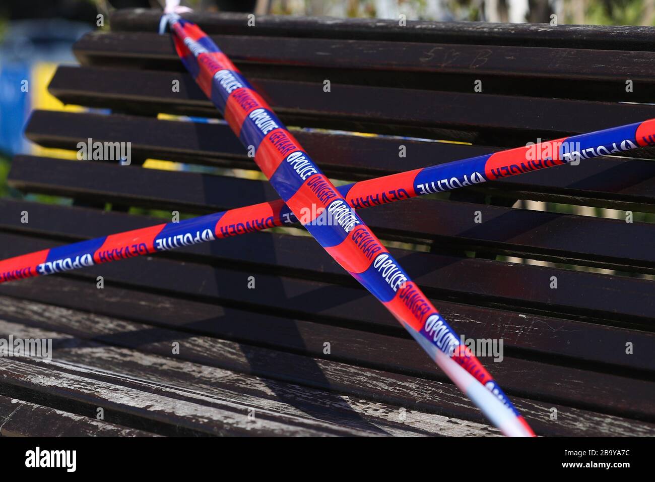 Brüssel, Belgien. März 2020. Eine Bank wird von der Polizei in einem Park in Brüssel, Belgien, am 25. März 2020 mit dem Barrikadenband verbunden gesehen. Bänke in Parks wurden zum Sitzen verboten, um zu verhindern, dass sich Menschen in den Parks sammeln oder zu lange aufhalten. Kredit: Zheng Huansong/Xinhua/Alamy Live News Stockfoto