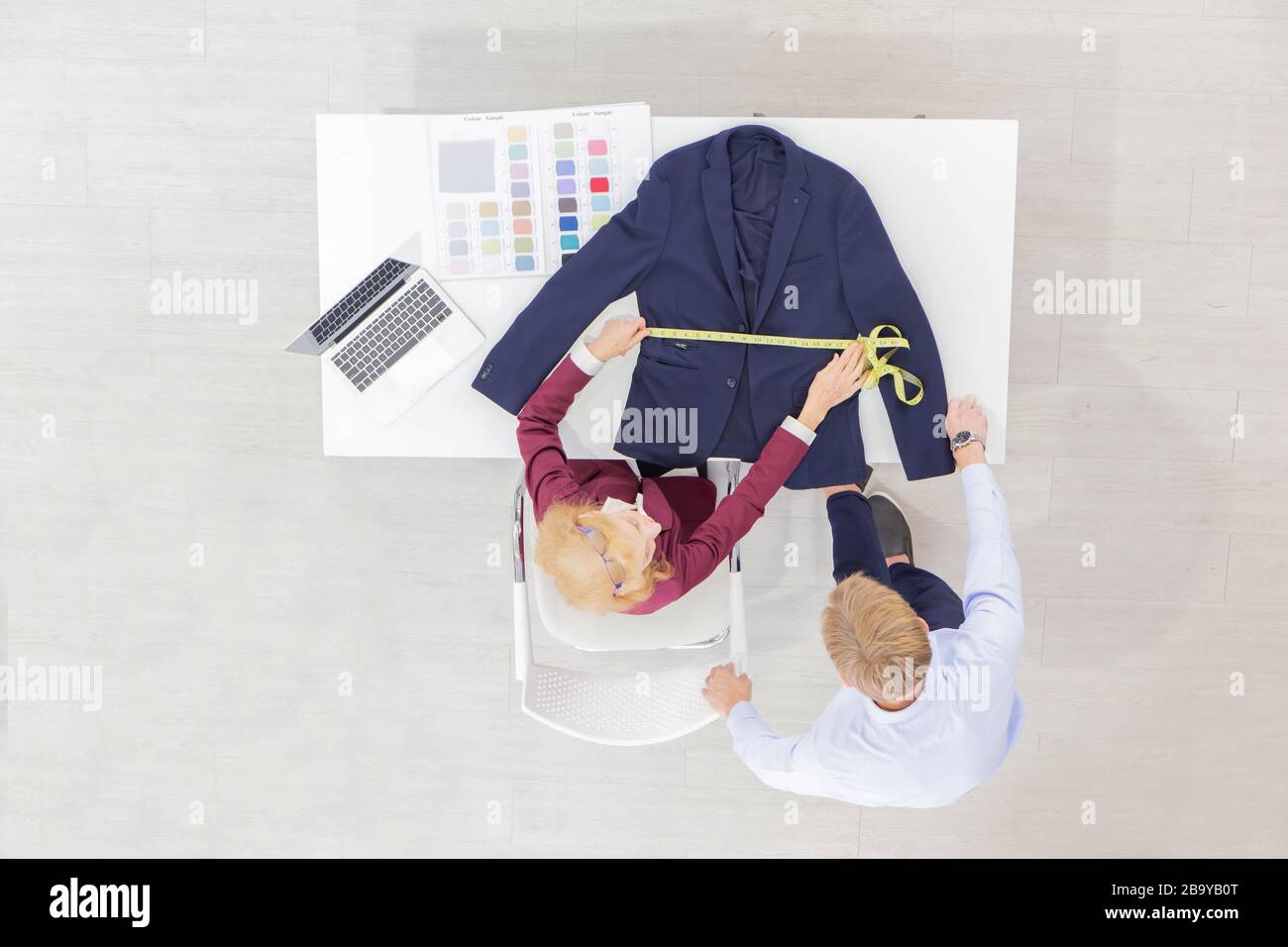 Topview professionelle Teamdesignerinnen, junge Männer und ältere Frauen im Büro mit verschiedenen Stofftönen und Geräten für verschiedene Designs. Stockfoto