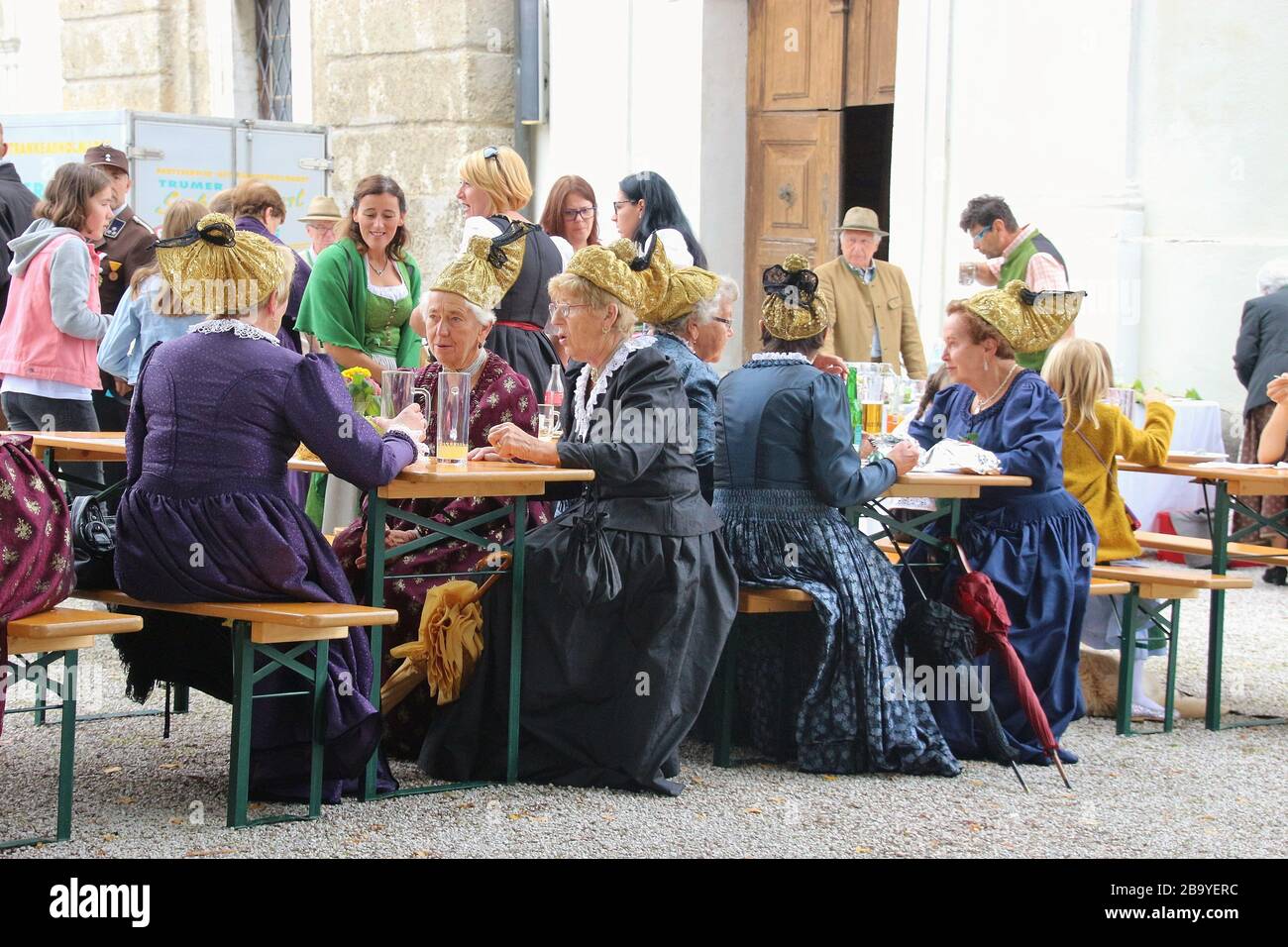 Bei einer Parochialfestlichkeit auf dem Land in Mattsee, Österreich, Europa. Die Leute sitzen zusammen. Frauen mit traditionellen Trachten und goldener Haube. Stockfoto