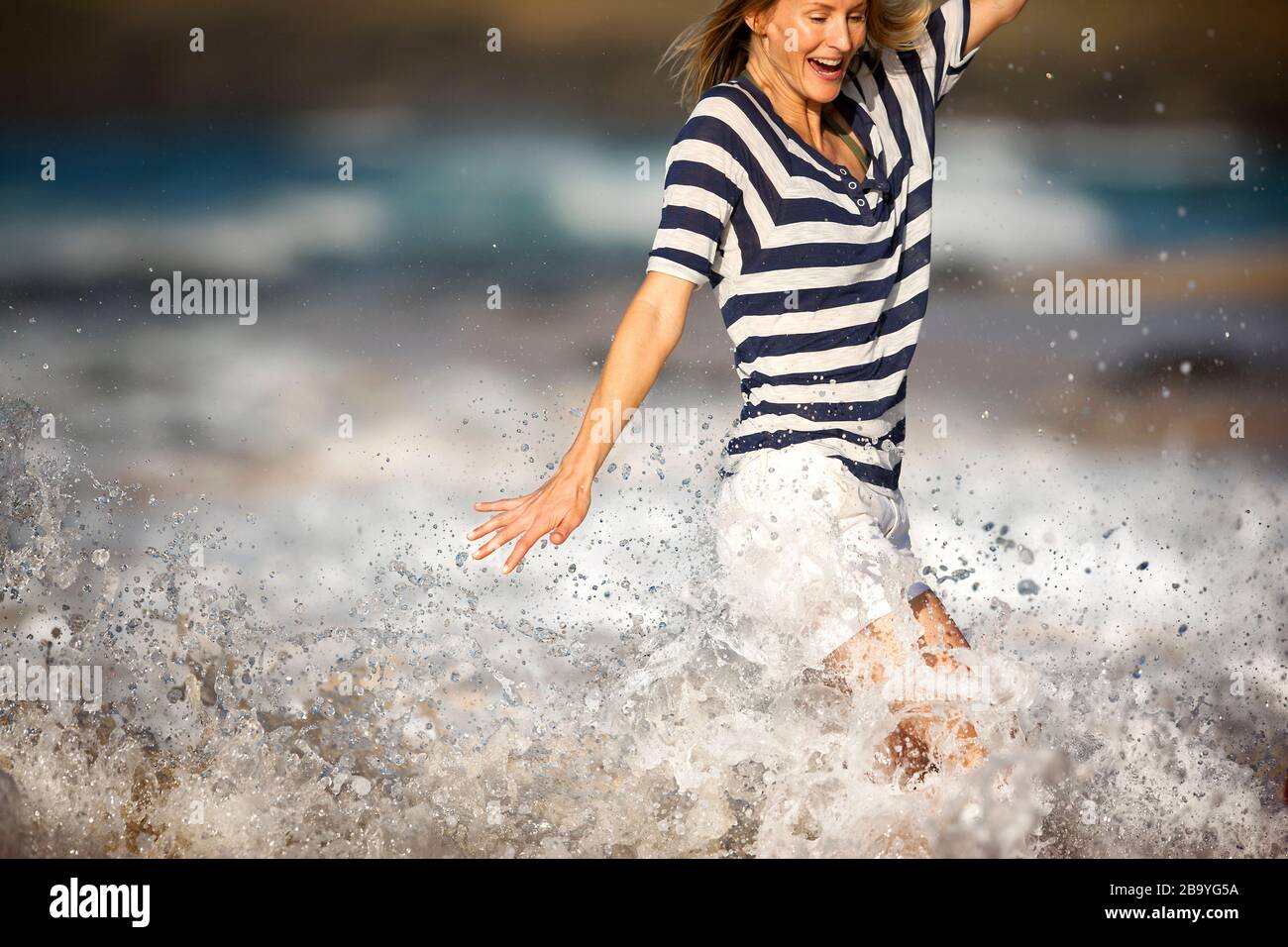 Frau, die von einer Welle zersplittert wird. Stockfoto