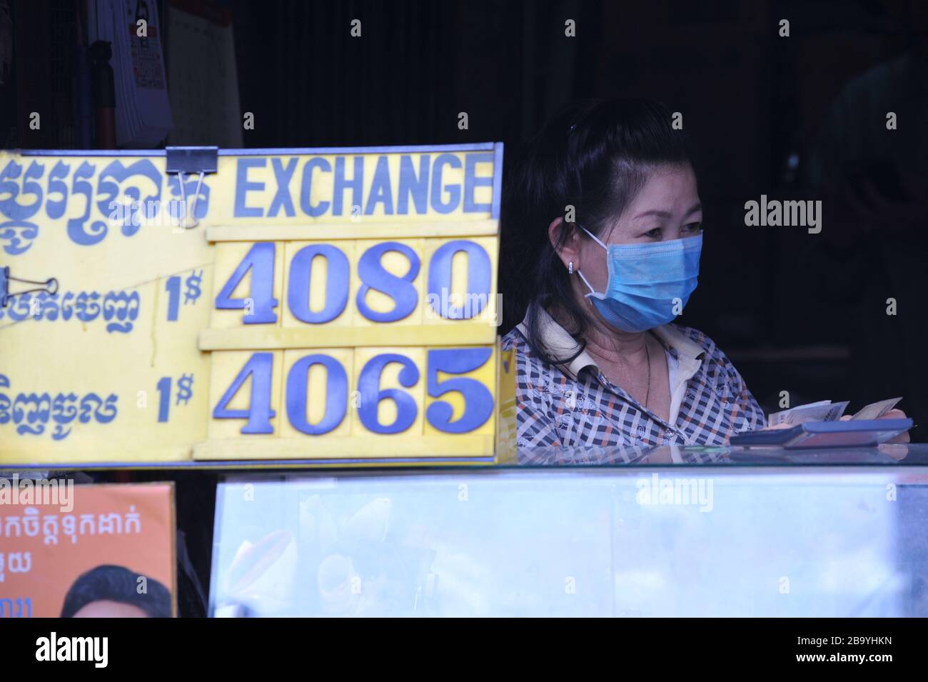 Eine kambodische Frau, die während der Coronavirus Pandemie eine Gesichtsmaske an einem Geldwechselstand trägt. Kandal Market, Phnom Penh, Kambodscha. © Kraig Lieb Stockfoto