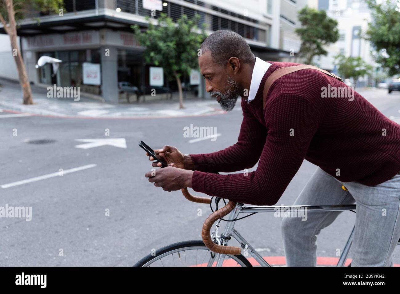 Afroamerikanischer Mann sitzt auf seinem Fahrrad und benutzt sein Telefon Stockfoto