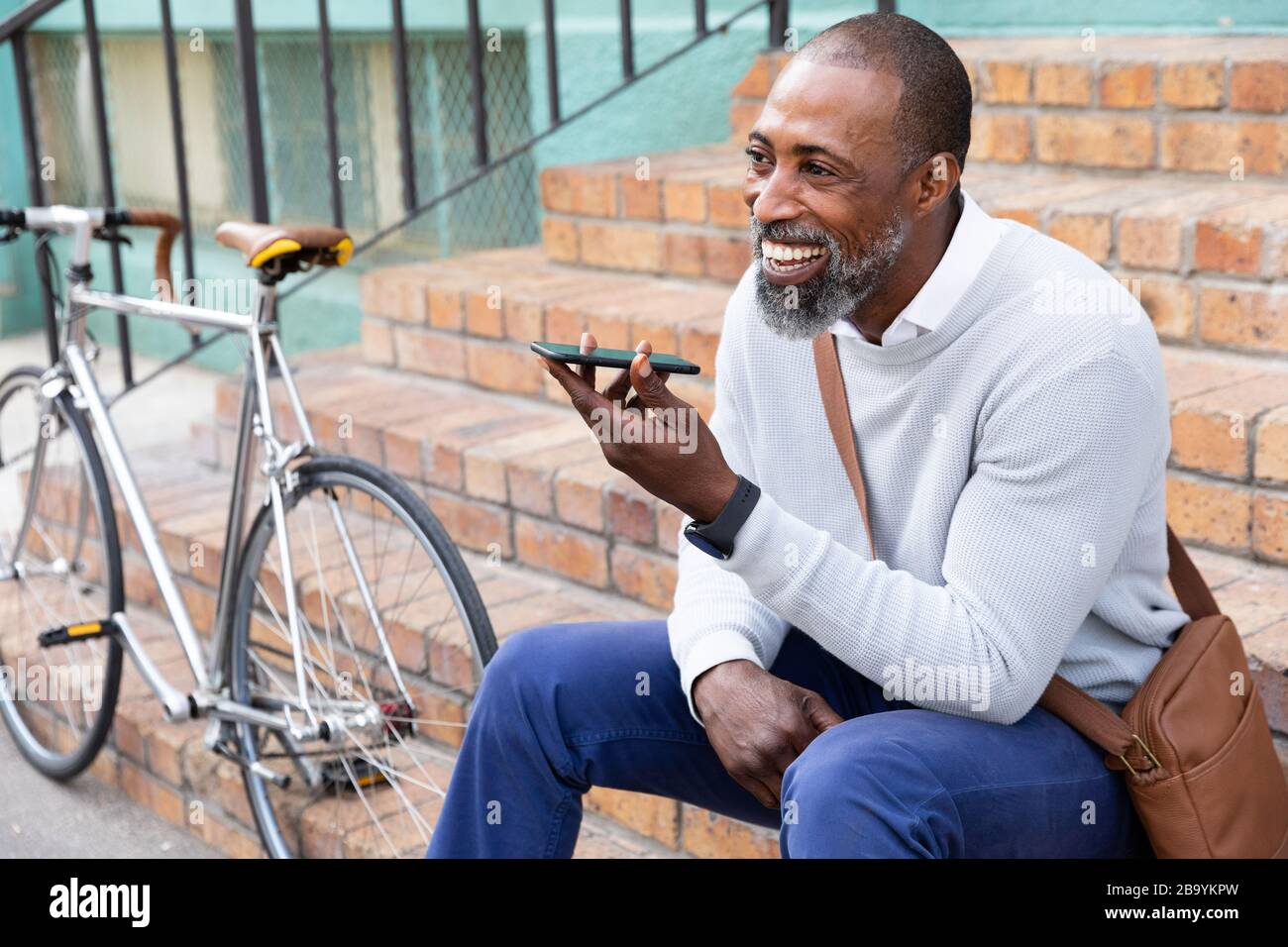 Afroamerikanischer Mann, der auf einer Treppe sitzt und einen Telefonanruf hat Stockfoto