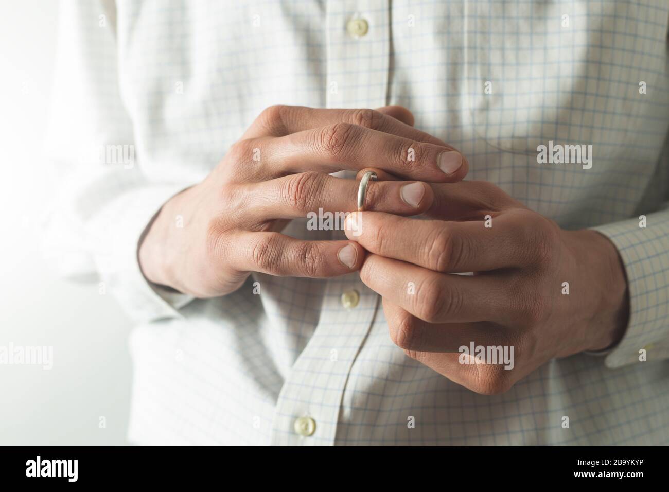 Ein Mann zieht einen Ehering von seinem Finger. Der Mann betrügt seine Frau. Das Konzept des Verrats. Stockfoto