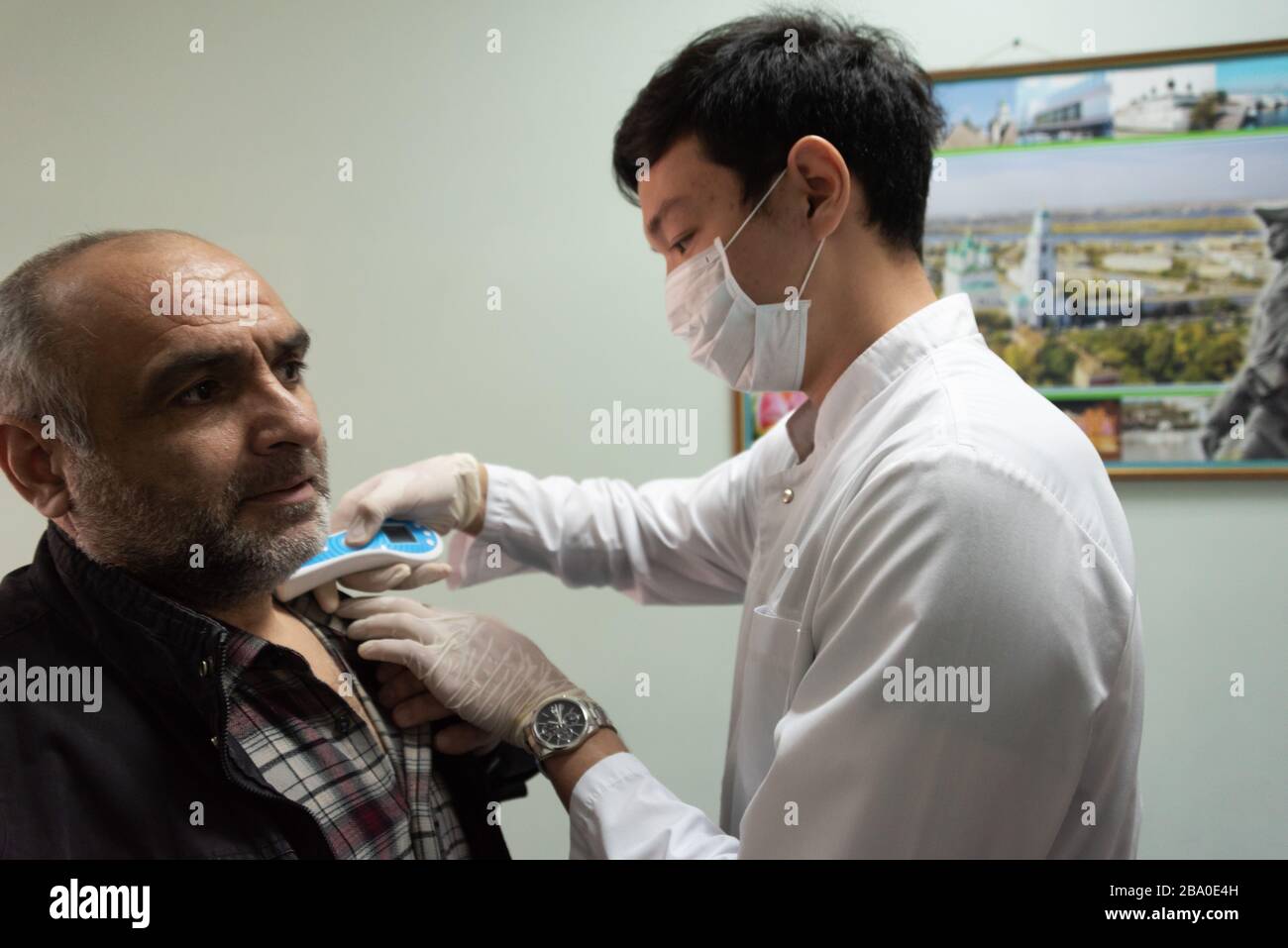 Medizinische Helfer in der Poliklinik messen die Temperatur der Patienten während der COVID-19-Coronavirus-Pandemie in Astrachan, Russland. Stockfoto