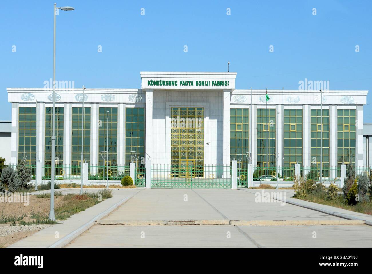 Fassade der Koneurgench Cotton Spinning Factory in Dashoguz, Turkmenistan. Mit weißem Marmor gebaut und mit Gold verziert. Turkmenische Textilindustrie. Stockfoto