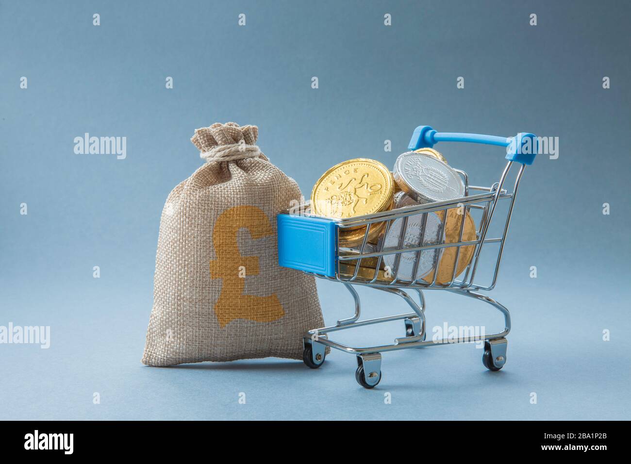 Ein Konzept eines Supermarkt-Einkaufswagens oder -Wagens voller Bargeld, Münzen und Geld, das die Verbraucherausgaben in Einzelhandelsgeschäften mit Kopierfläche repräsentiert Stockfoto