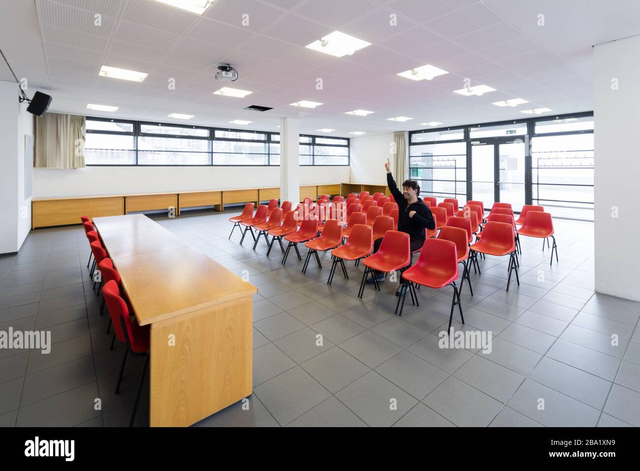 Einsamer Mann im Konferenzraum mit roten Stühlen Stockfoto