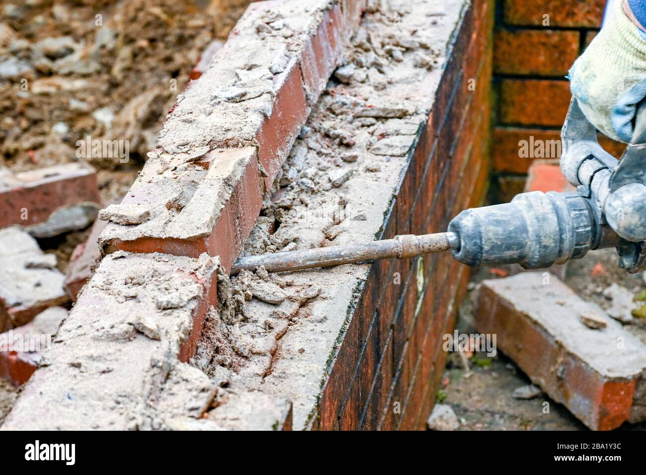 CARDIFF, WALES - JANUAR 2020: Arbeiter, die mit einem Stromhammer Ziegelsteine in einer alten Mauer aufbrechen. Stockfoto