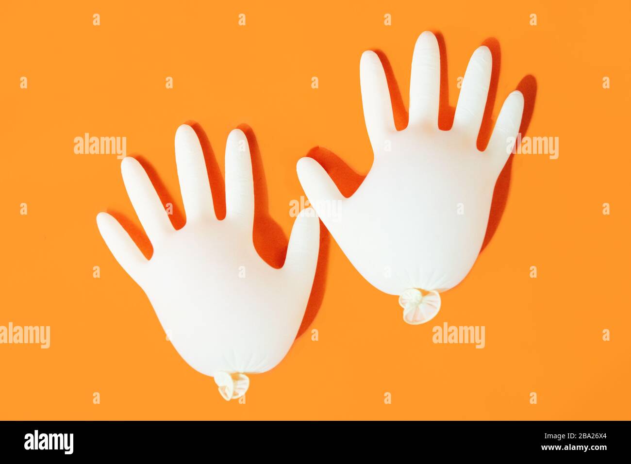 Weiße medizinische Handschuhe isoliert auf orangefarbenem Hintergrund. Schutz Stockfoto