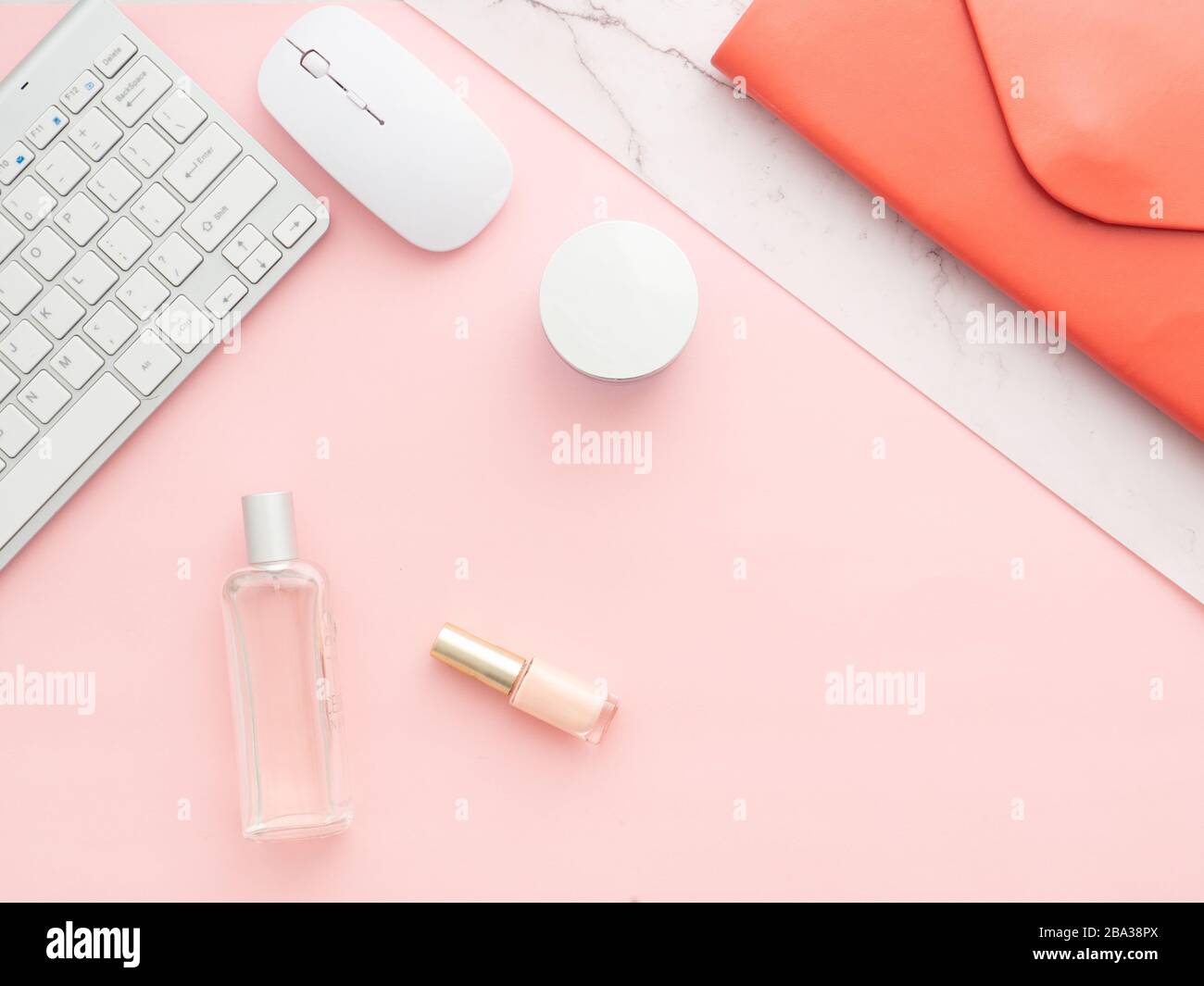Flaches Lay, Draufsicht auf den rosafarbenen Tischrahmen. Femininer Arbeitsplatz mit Laptop, roter Ordnerkupplung, heilende Kosmetik, Computertastatur und Maus i Stockfoto