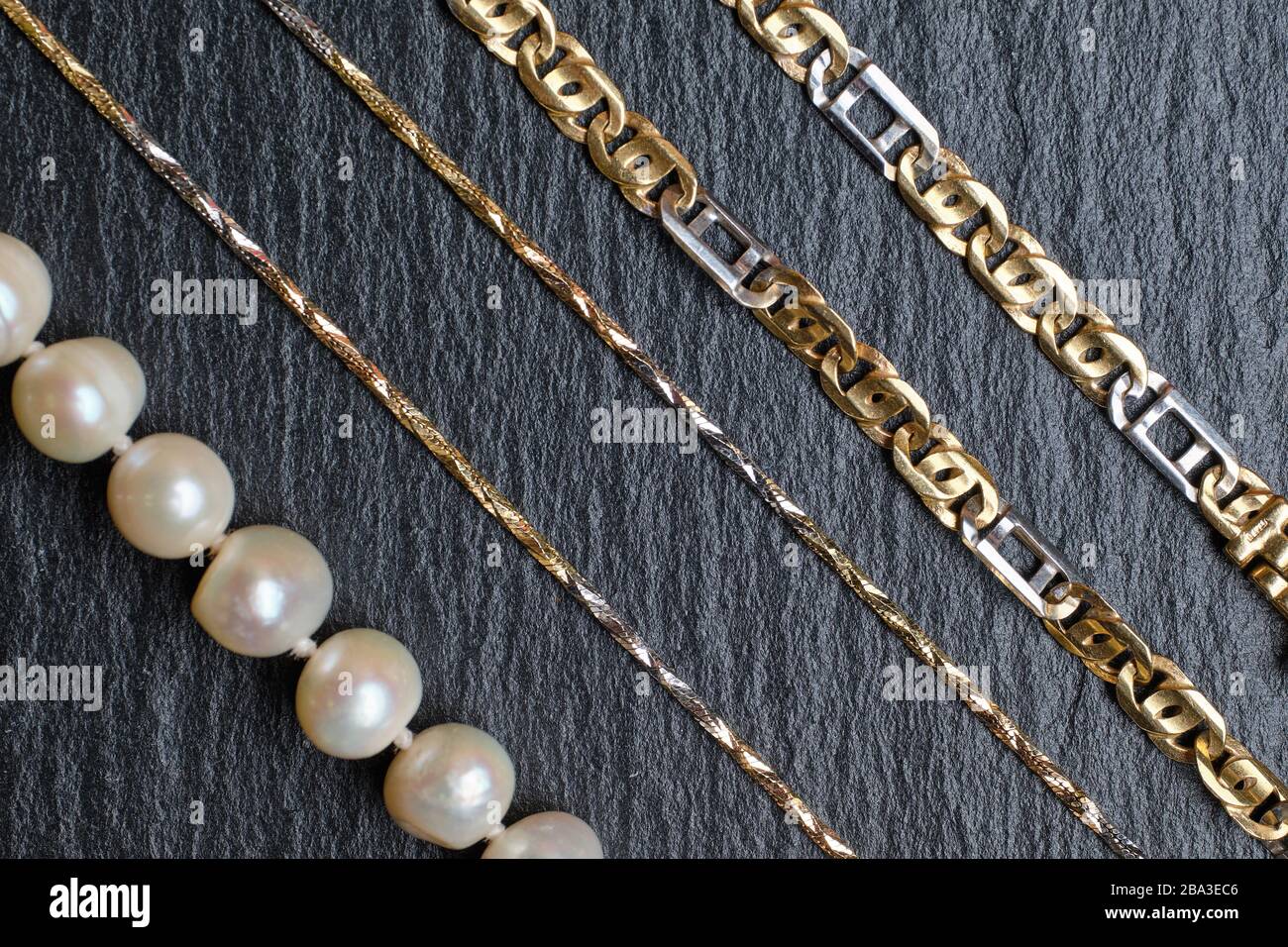 Verschiedene Arten von Goldketten und Perlen auf einem Steinbrett.  Nahaufnahme Stockfotografie - Alamy