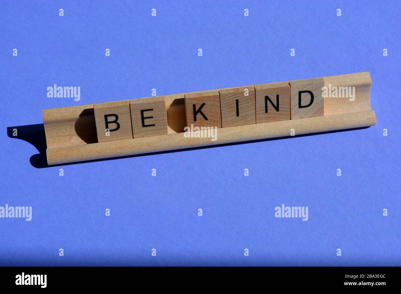 Seien Sie freundlich, Buchstaben aus Holzalphabet auf blauem Hintergrund mit Kopierraum Stockfoto