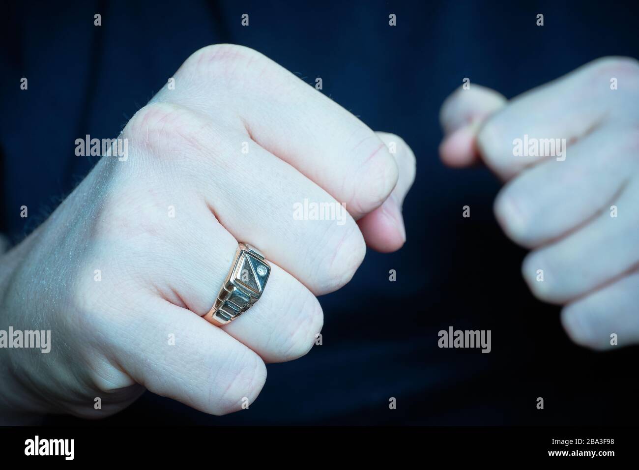 Der Mann legte bedrohlich Fäuste mit einem Ring auf. Blau getont. Nahaufnahme. Stockfoto