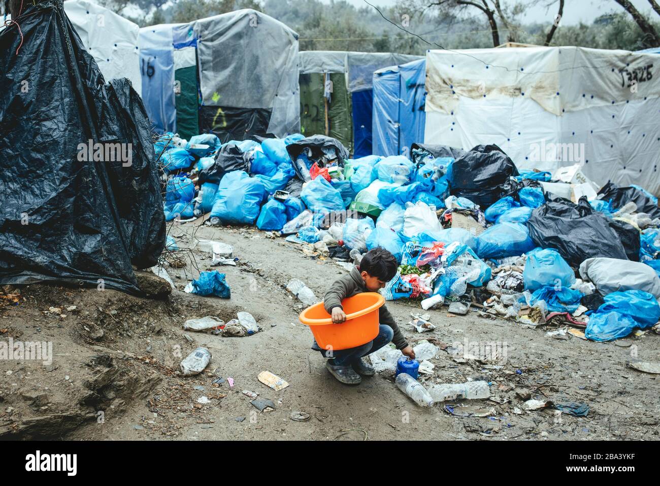 Das Kind sammelt Utensilien aus dem Müll im Flüchtlingslager in Moria, Lesbos, Griechenland Stockfoto