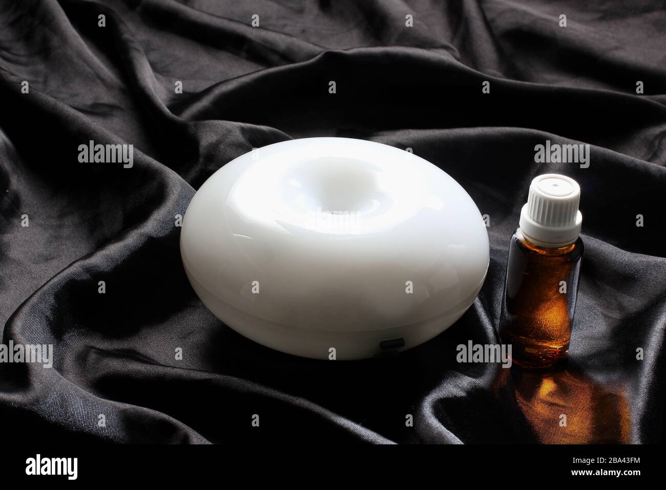 Luftdiffusor mit ätherisches Öl auf schwarzer Seide Stockfotografie - Alamy
