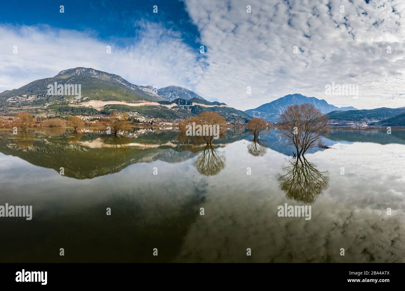 Flug über das überschwemmte Tal in Griechenland. Die überfluteten Felder, Straßen, Berge im Hintergrund, die bewohnte Siedlung. Reflexion der Berge in Stockfoto