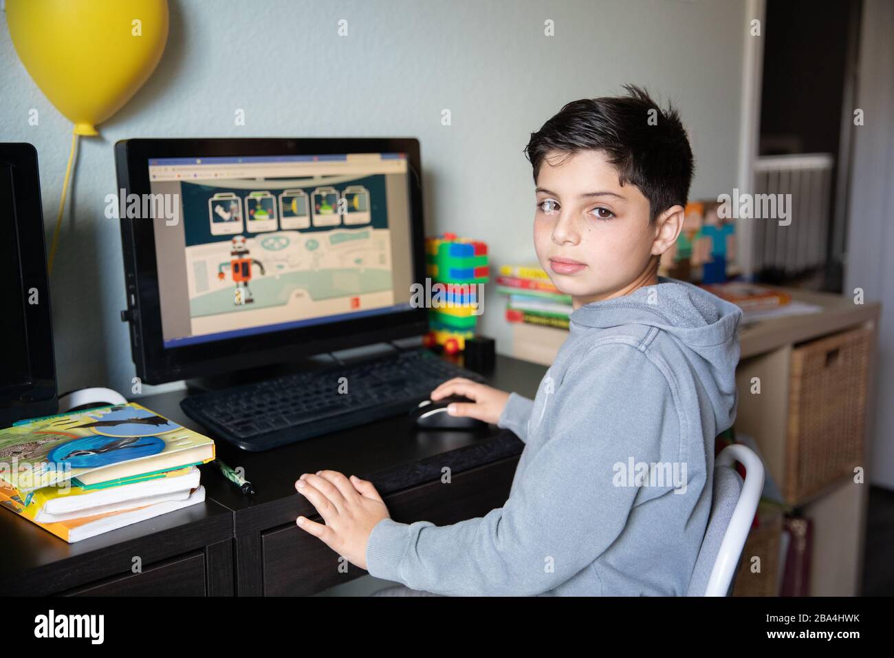 Niedlicher kleiner Junge, der zu Hause auf dem Computer aufgrund von Schulschließungen wegen des Ausbruchs des Corona-Virus in der Welt studiert. Stockfoto