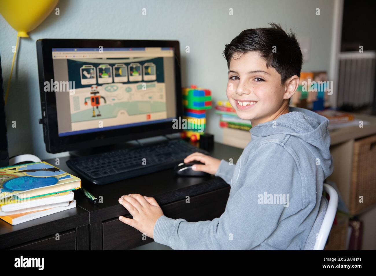 Niedlicher kleiner Junge, der zu Hause auf dem Computer aufgrund von Schulschließungen wegen des Ausbruchs des Corona-Virus in der Welt studiert. Stockfoto