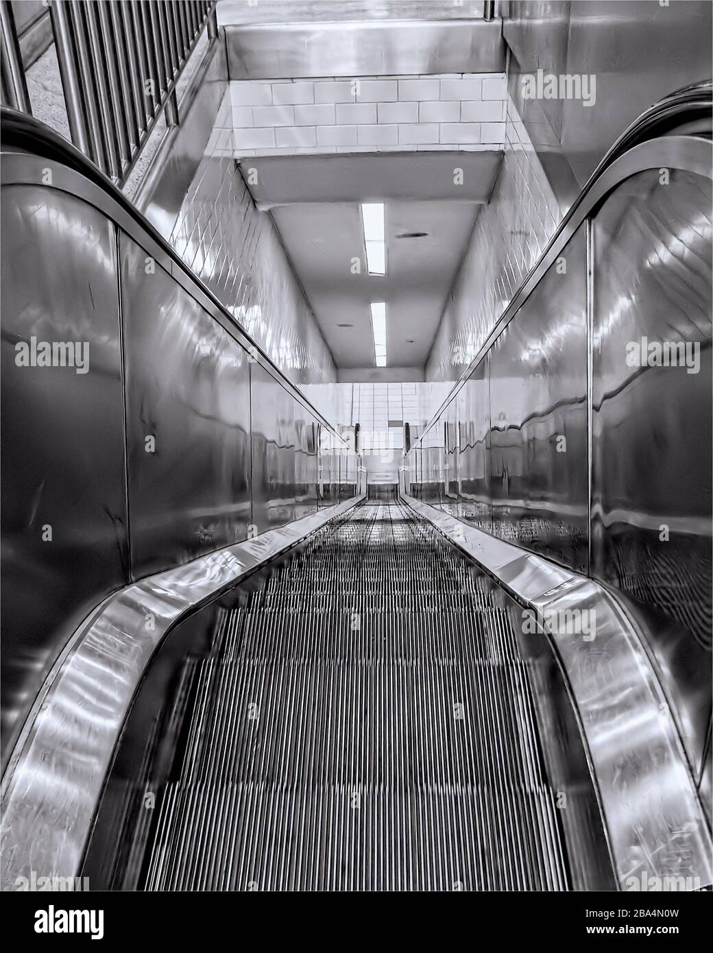 Nahaufnahme der schwarz-weißen Rolltreppe aus glänzendem Metall mit führenden Linien. Stockfoto