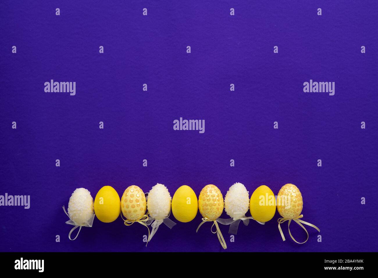 Osterweiß und Gelb dekorative Eier aus Kunststoff auf dunkelviolettem Grund Stockfoto