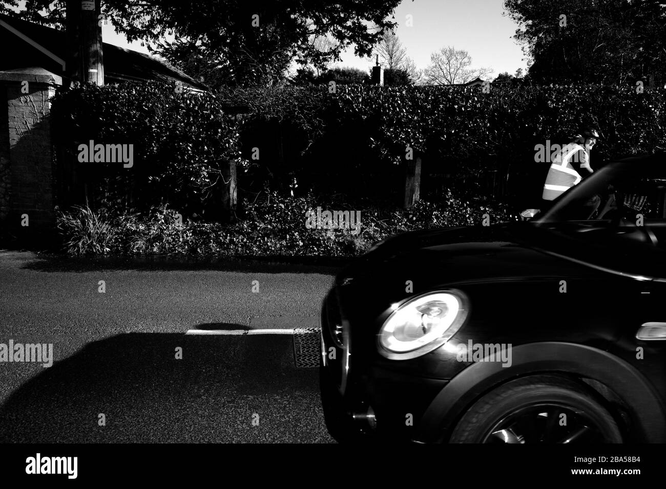 Radfahrer und Auto fahren auf der Straße aneinander vorbei Stockfoto